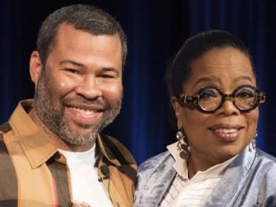 Jordan Peele and Oprah Winfrey are side-hugging each other as they are smiling for the picture.